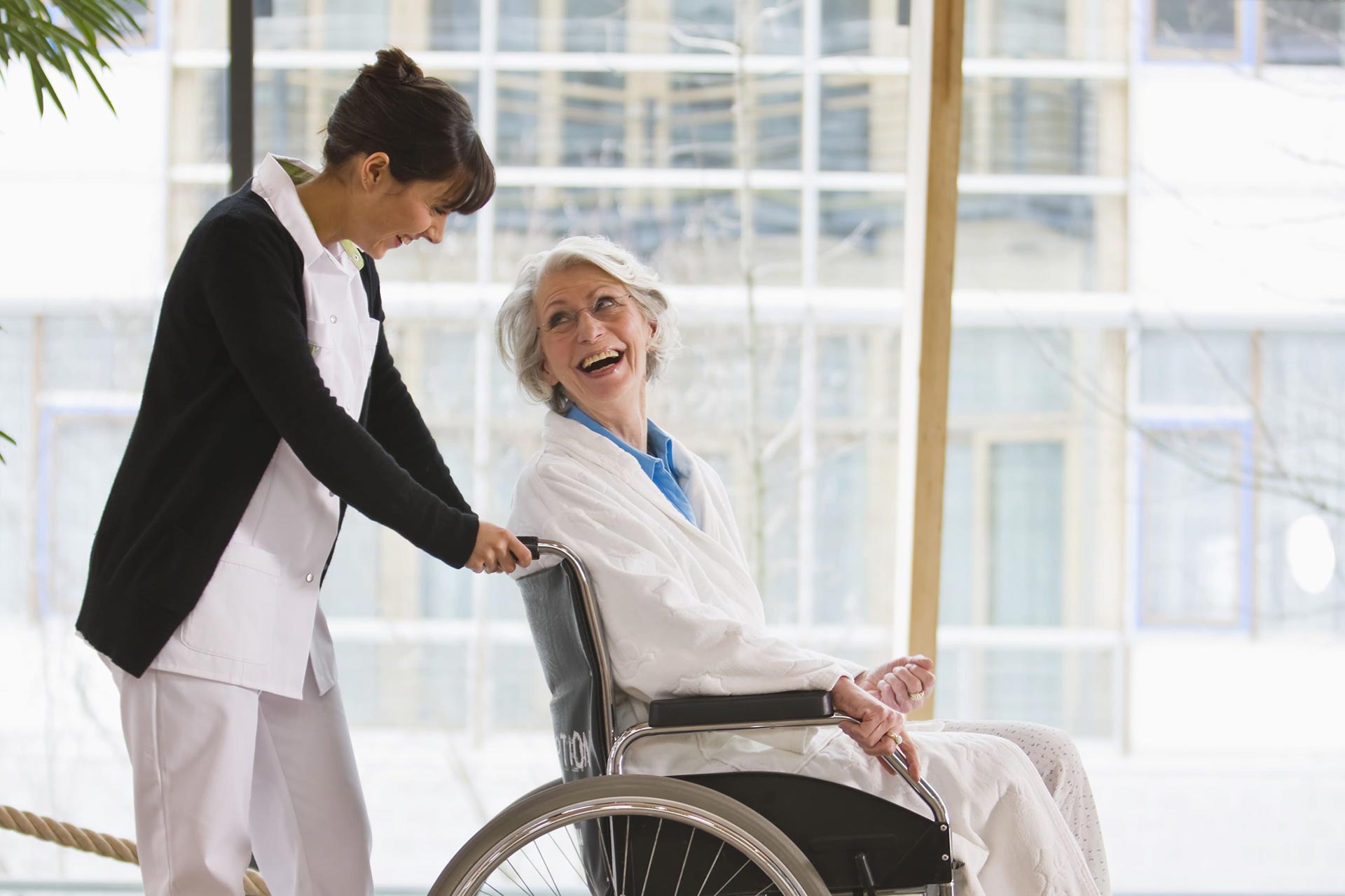 Infirmière poussant une personne âgée dans un fauteuil roulant